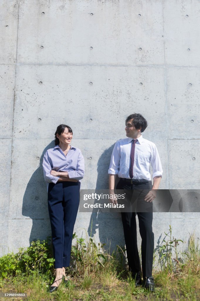 Man and woman standing in front of concrete wall