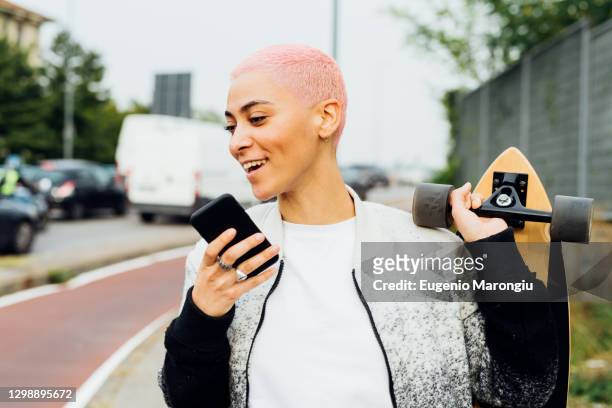 skateboarder walking and using cellphone - woman talking cellphone stock-fotos und bilder