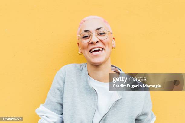 portrait of happy young woman with short pink hair, wearing glasses - abrigo rosa fotografías e imágenes de stock