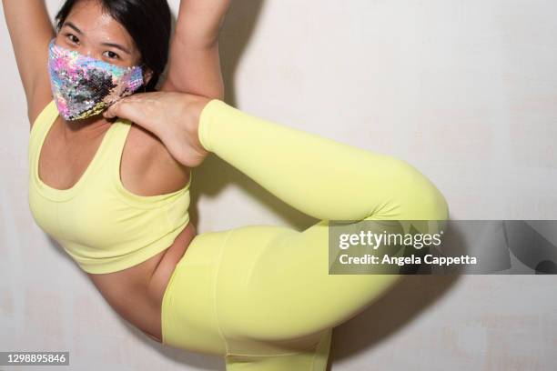 contortionist with foot raised, wearing face mask - contortionist stock pictures, royalty-free photos & images