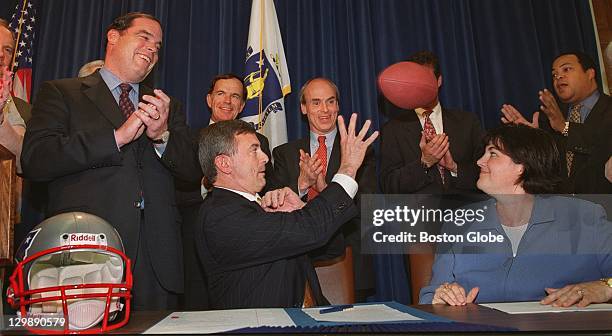 Governor Paul Cellucci throws a football to Don Lowery, right, spokesperson for the New England Patriots, after the Governor and Lt. Governor Jane...