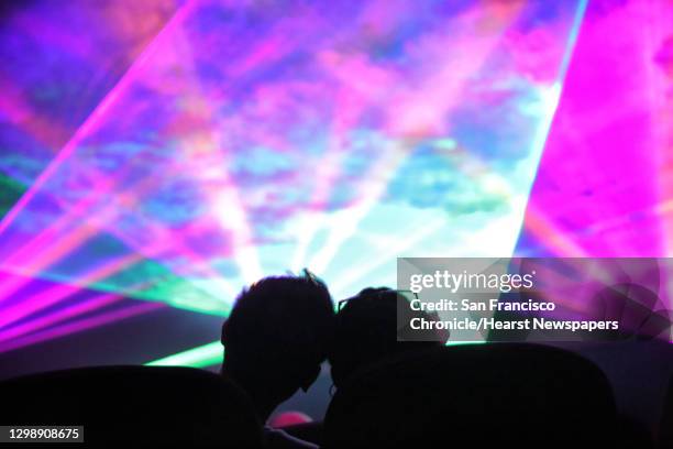 Couple watches from the back row as local music artist and DJ Stastia Irons, aka Stas THEE Boss, performs during a laser light show at the Pacific...