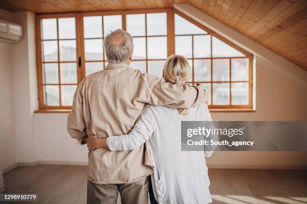 happy senior couple in their empty new apartment - senior moving house stock pictures, royalty-free photos & images