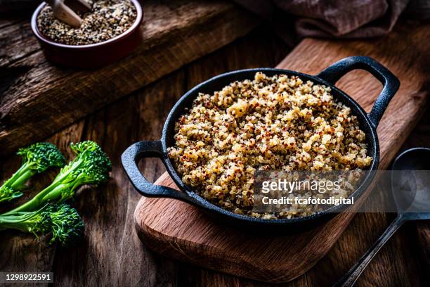 cooked quinoa in a cast iron pan on rustic wooden table. - quinoa meal stock pictures, royalty-free photos & images