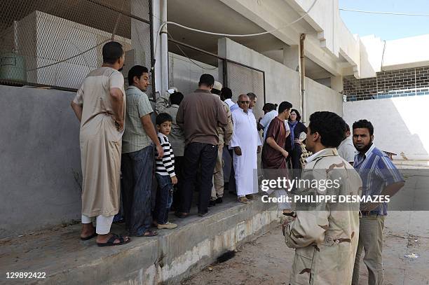 Libyans queue to view the body of ousted Libyan strongman Moamer Kadhafi inside the cold storage room of a vegetable market near a mosque in the...