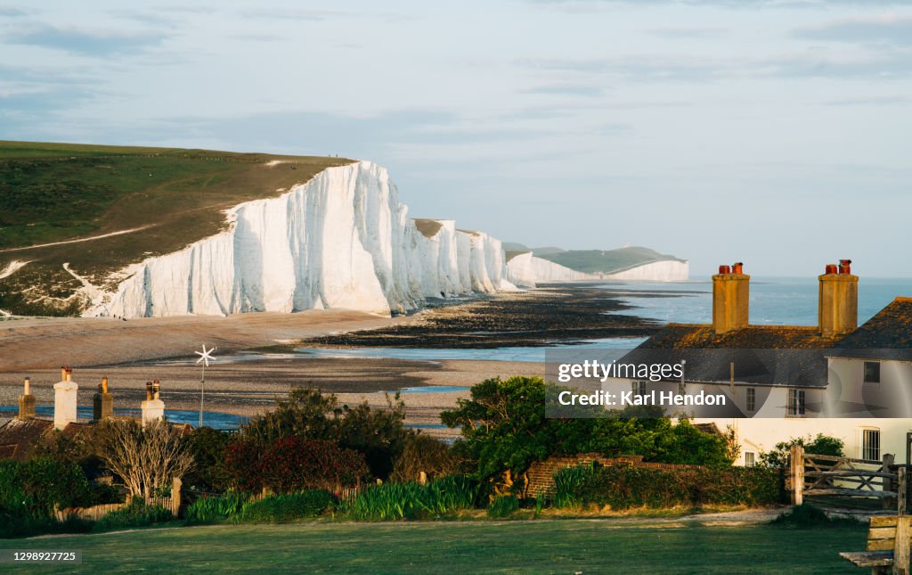 A daytime view of the Seven Sisters cliffs and cottages on the East Sussex coast - stock photo