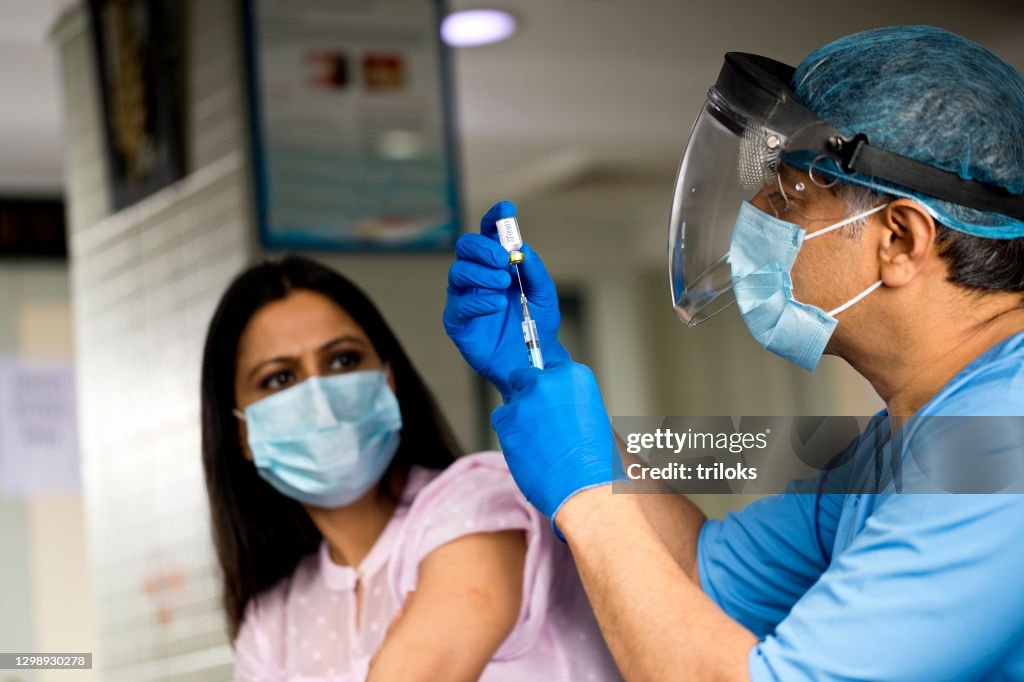 Doctor preparing Covid-19 vaccine for female patient