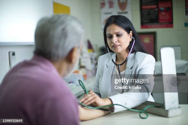 female doctor measuring blood pressure of old male patient - medical insurance stock pictures, royalty-free photos & images