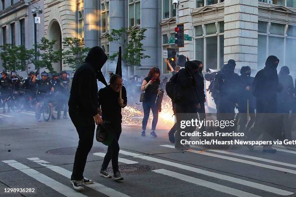 Demonstrators run from a blast ball SPD officers used to disperse the crowd during the annual anti-capitalist May Day march through downtown Seattle,...