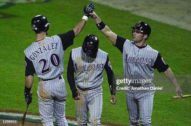 Shortstop Tony Womack of the Arizona Diamondbacks walks under the celebration bridge as leftfielder Luis Gonzalez congratulates pinch hitter David...