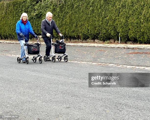 zwei ältere erwachsene unterwegs, beide mit spaziergängern. - rollator stock-fotos und bilder
