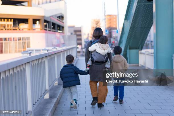 de rug van een moeder met haar drie kinderen - woman hand crossed stockfoto's en -beelden