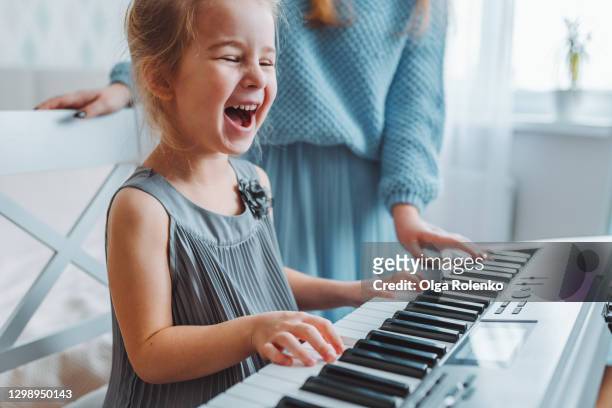 toddler blonde girl sing and play piano at home. - children music stockfoto's en -beelden