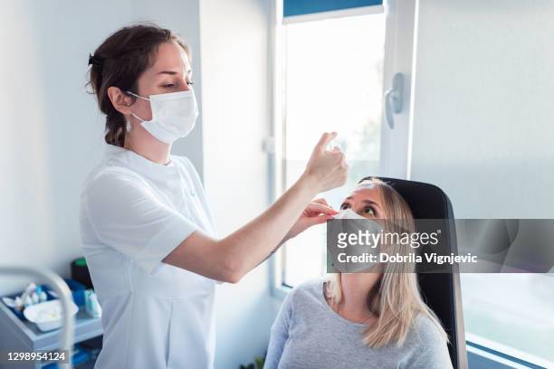 nurse wearing a protective face mask and examining patient's eyes - dry eye stock pictures, royalty-free photos & images
