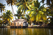 House-boat pleasure cruise ship in India, Kerala on the seaweed-covered river channels of Allapuzha in India. Boat on the lake in the bright sun and palm trees among the tropics. Sight Houseboat