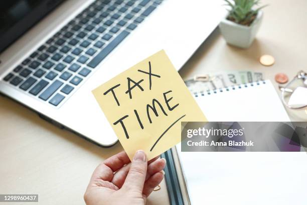 note pad with pencils, laptop, eyeglasses, money and office supplies on wooden table, concept of tax time or tax day. - tax season stock pictures, royalty-free photos & images