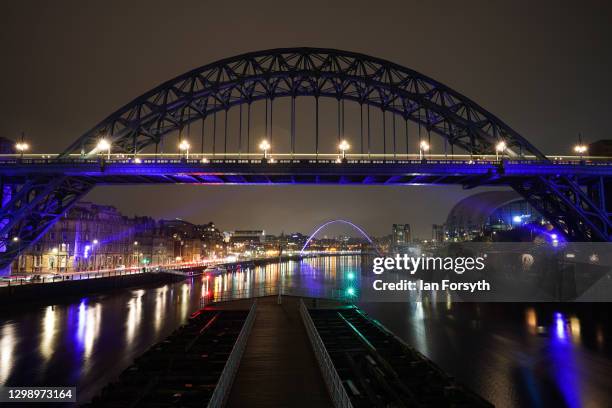 The Tyne Bridge and beyond it the Millennium Bridge in Newcastle are bathed in purple light to commemorate Holocaust Memorial Day on January 27, 2021...