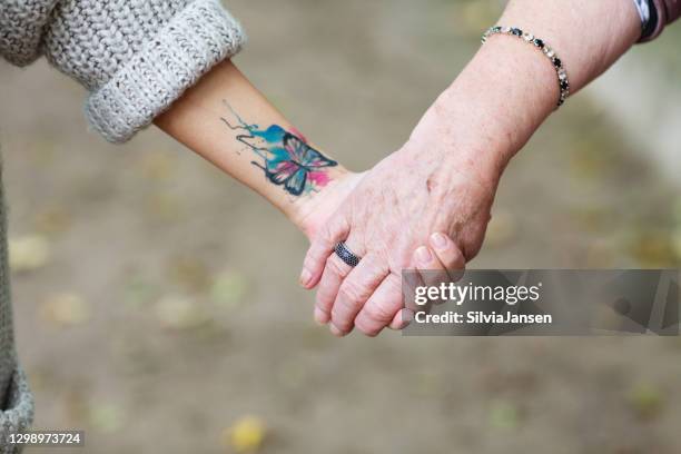 young woman holding hand of a senior adult - old woman tattoos stock pictures, royalty-free photos & images