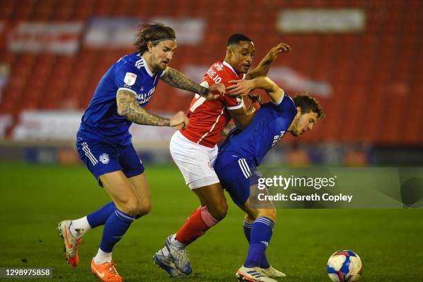 Victor Adeboyejo of Barnsley is challenged by Aden Flint and Will Vaulks of Cardiff City during the Sky Bet Championship match between Barnsley and...