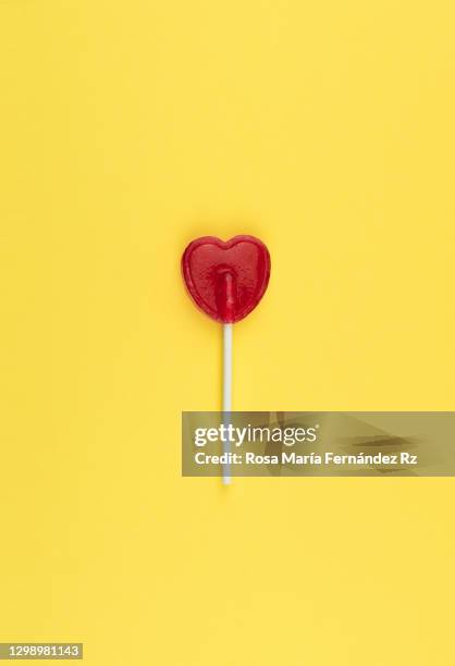 concept of love and romanticism. one red heart-shaped lollipop  against yellow background. - lollipop background stock pictures, royalty-free photos & images