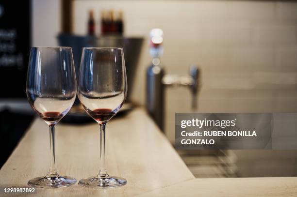 close-up front view of two empty crystal wine glasses on a bar table with a metallic bucket with some opened wine bottles with cork and a beer faucet without jar at the back. horizontal photography. - wine cork stockfoto's en -beelden