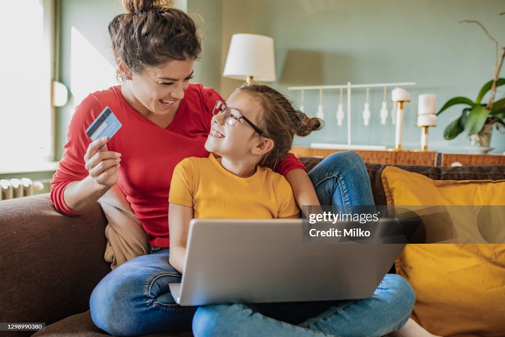 Mother and daughter at home using laptop for online shopping