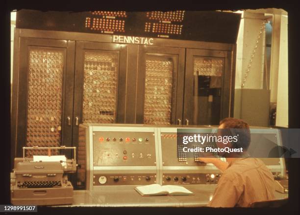 Operator sits at the control board of Pennstac , one of the first, university, large-scale computers , State College, Pennsylvania, 1964.