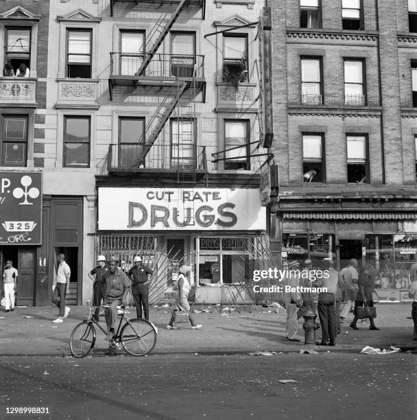 Broken metal gates and smashed windows of this Harlem drug store on Lenox Avenue near 128th Street bear morning-after testimony to the violence of...