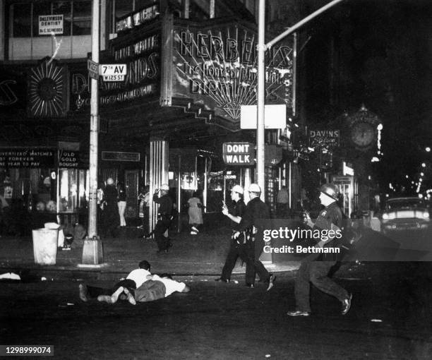 Police officers with drawn revolvers hasten to scene of Herbert's jewelry store as rioters and potential looters threaten the area at 125th Street...