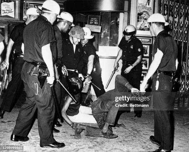 Steel-helmeted riot police close in on a man and woman who ignored an order to move during third night of violence in Harlem. Demonstrations...