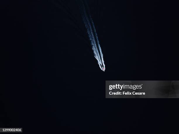aerial view of a speedboat on the move against dark deep blue waters. - speedboat stock-fotos und bilder