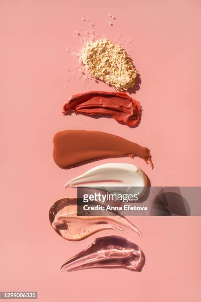 row of smears of assorted cosmetic products and face powder on pink background. trendy selfcare products of the year - couleur crème photos et images de collection