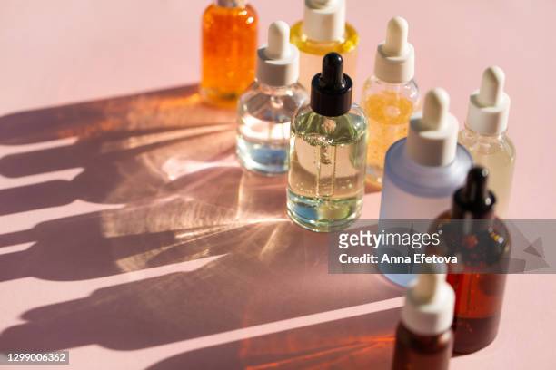 bottles of aromatic cosmetic products on pink background. trendy selfcare products of the year - enzymes cosmetics stockfoto's en -beelden
