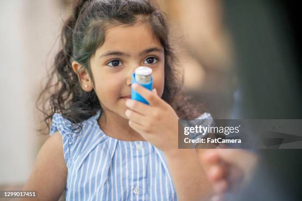 niña joven que usa un inhalador para el asma - asmático fotografías e imágenes de stock