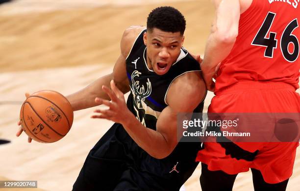 Giannis Antetokounmpo of the Milwaukee Bucks drives on Aron Baynes of the Toronto Raptors during a game at Amalie Arena on January 27, 2021 in Tampa,...