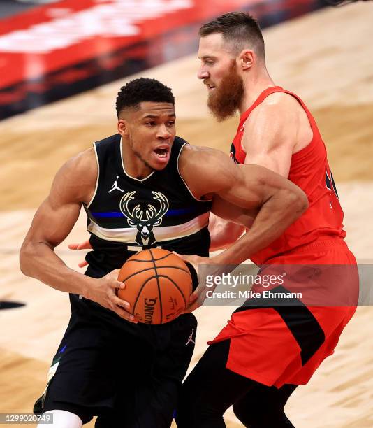 Giannis Antetokounmpo of the Milwaukee Bucks drives on Aron Baynes of the Toronto Raptors during a game at Amalie Arena on January 27, 2021 in Tampa,...