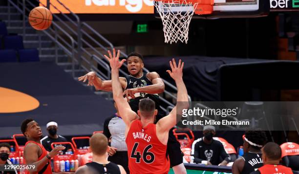 Giannis Antetokounmpo of the Milwaukee Bucks passes over Aron Baynes of the Toronto Raptors during a game at Amalie Arena on January 27, 2021 in...