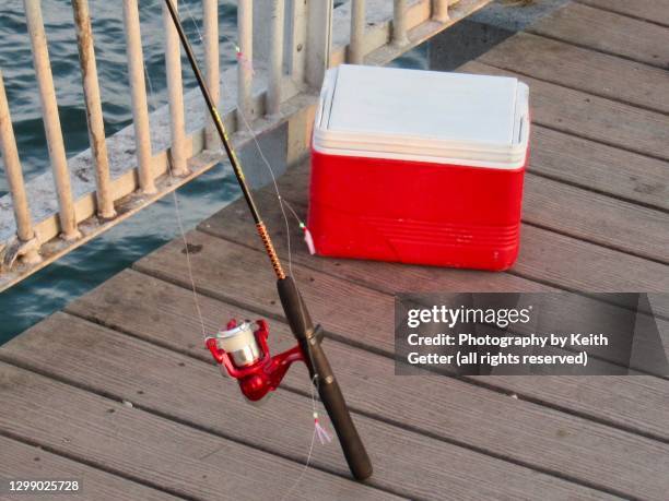 gone fishing: a fishing rod and reel next to a cooler at the edge of a pier - gone fishing stock pictures, royalty-free photos & images