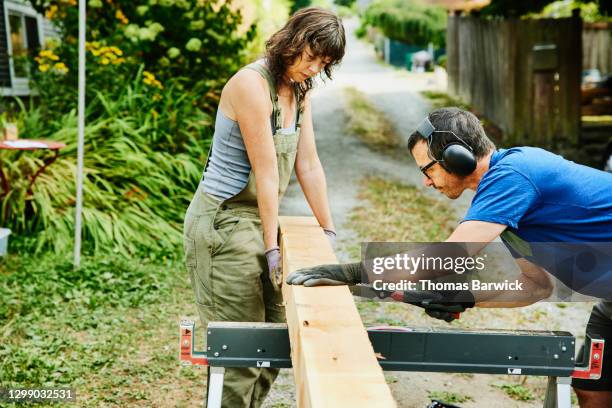 couple cutting lumber for home improvement project - iemand een plezier doen stockfoto's en -beelden