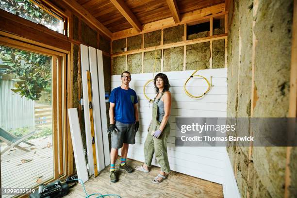 portrait of smiling couple standing in room being remodeled during home improvement project - couple working from home stock pictures, royalty-free photos & images