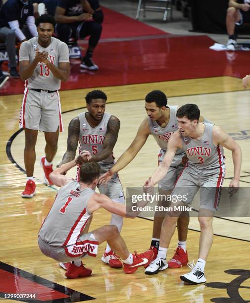 Bryce Hamilton of the UNLv Rebels claps as David Jenkins Jr. #5, Devin Tillis and Caleb Grill of the Rebels help teammate Moses Wood off the floor...