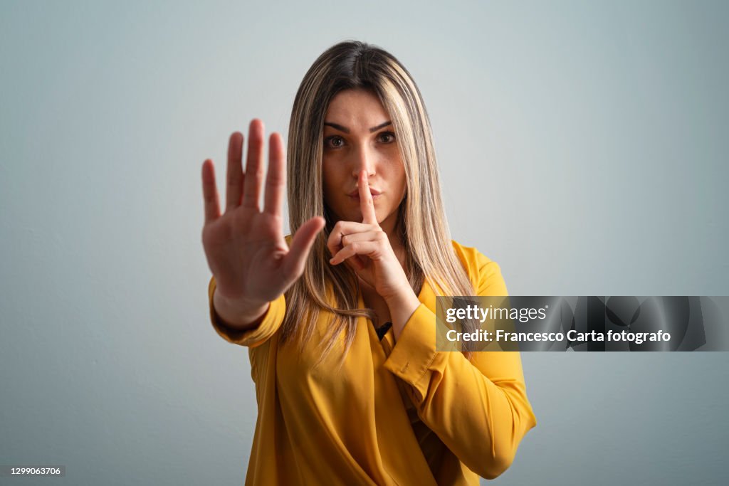 Woman with finger on lips showing Stop Sign