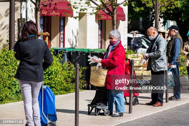 File d'attente avec distanciation physique devant un commerce d'alimentation, des gens enfilent des gants de protection lors du confinement suite au...