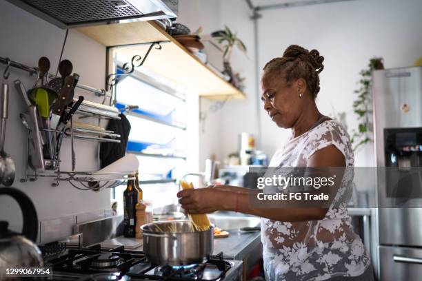 senior woman cooking pasta at home - stay at home mum stock pictures, royalty-free photos & images