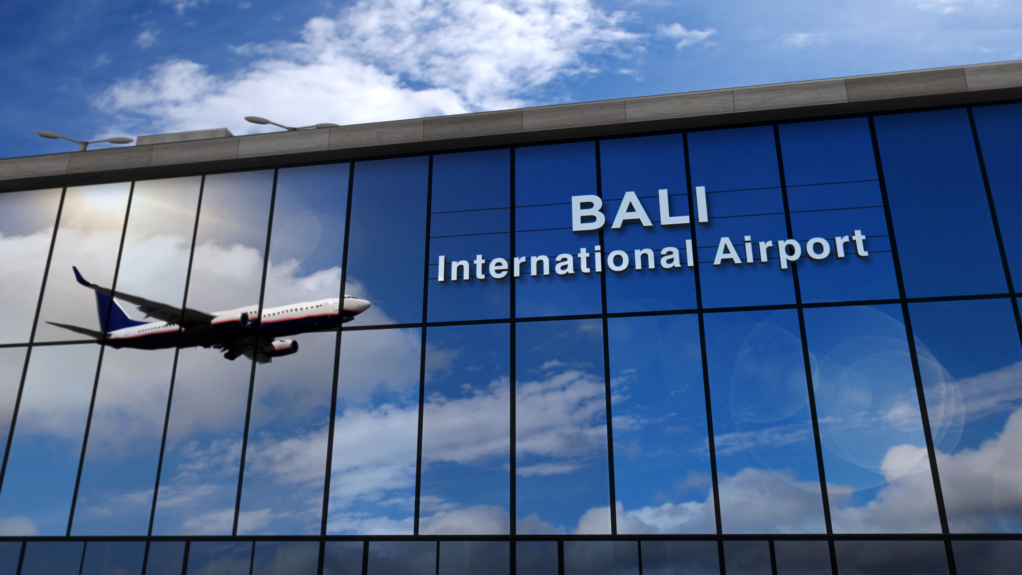 Airplane landing at Bali Indonesia airport mirrored in terminal Airplane landing at Bali Indonesia airport mirrored in terminal