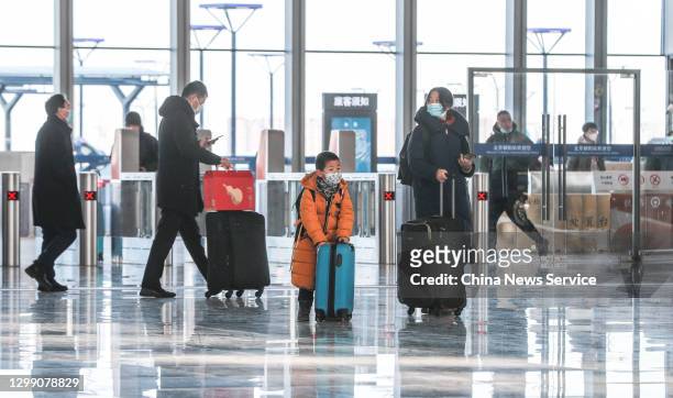 Passengers wearing face masks arrive at Beijing Chaoyang Railway Station on the first day of the 40-day Spring Festival travel rush on January 28,...