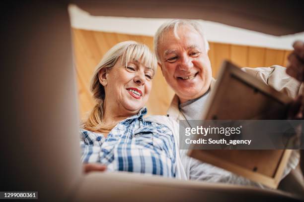 senior couple unpacking cardboard box together - memories box stock pictures, royalty-free photos & images