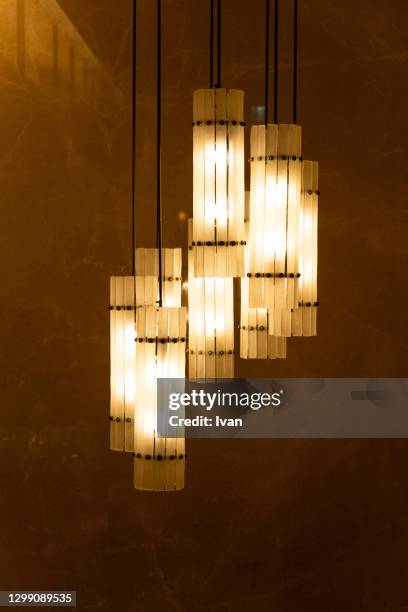 low angle view of illuminated modern chandelier hanging on ceiling - ceiling lamp stockfoto's en -beelden