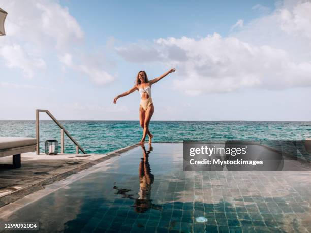 gelukkige vrouw loopt op de rand van een infinity pool in de malediven - infinity loop stockfoto's en -beelden