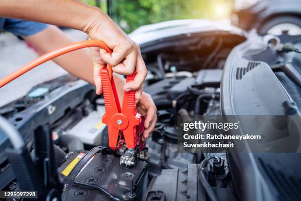 close up of auto mechanic jumping battery car. - autobatterie stock-fotos und bilder